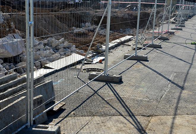 a group of construction workers working behind temporary fence panels for safety